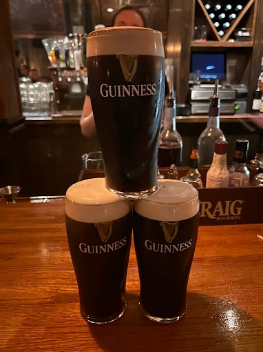 Three pints of Guinness stacked on the wooden bar at O'Pub.