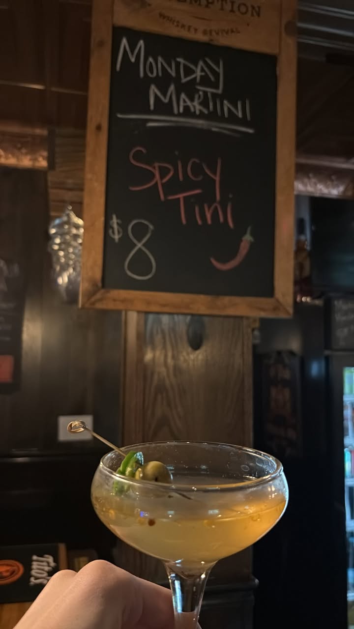 A spicy martini held up in front of the chalkboard at O'Pub.